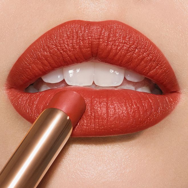 Limitless Lucky Lips in Love flame on lips close-up Lips close-up of a medium-tone model wearing tawny orange-red lipstick with a matte finish.