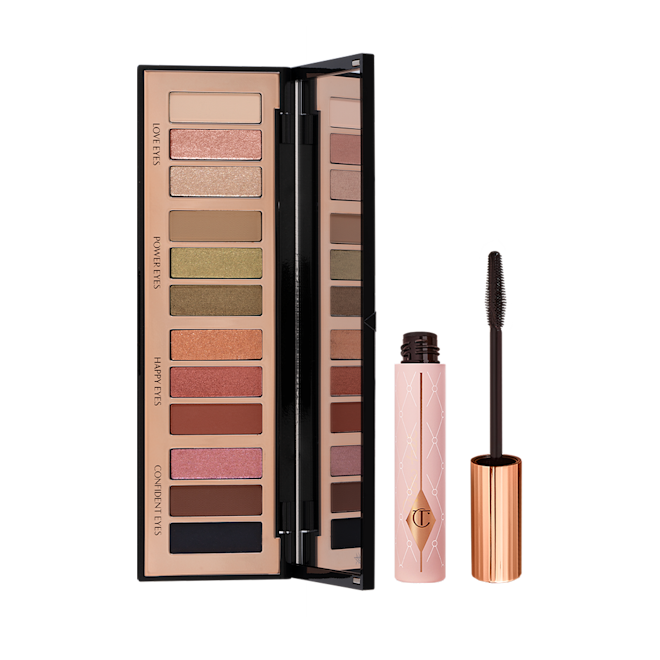 Smokey Eyes Are Forever Kit open Black mascara in a sheer pink tube with a gold coloured lid and fluffy applicator and an open, 12-pan eyeshadow palette with a mirrored-lid with pink, gold, green orange, red, brown, black, and beige shades to create different smokey eye looks.
