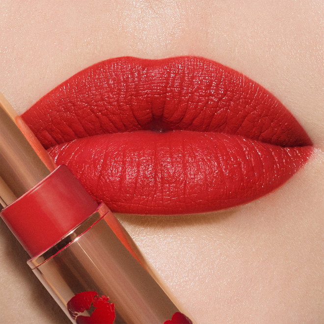 Lips close-up of a fair-tone model wearing poppy red lipstick with a matte finish.
