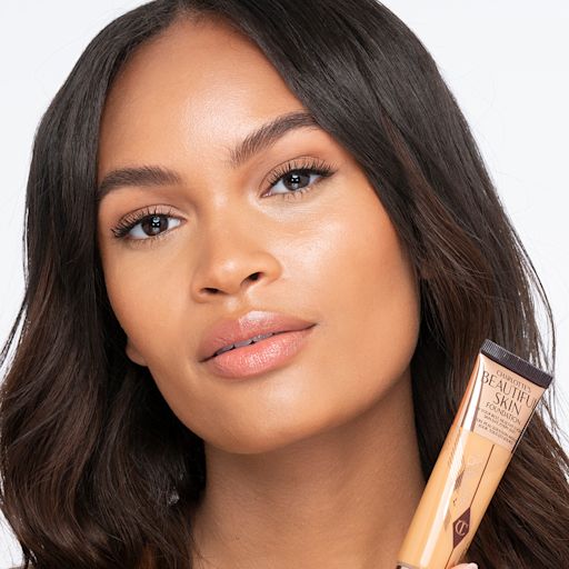 Beautiful Skin Foundation in 9W on medium-dark-tone model Medium-dark-tone brunette model wearing glowy, skin-like foundation with a satin finish with nude lipstick and subtle eye makeup.
