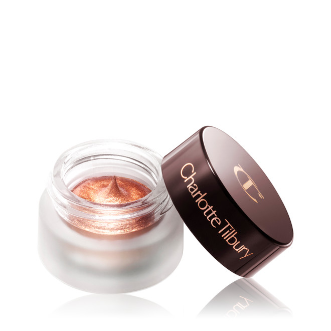 A coppery gold. cream eyeshadow in an open glass pot with a dark brown-coloured lid. 