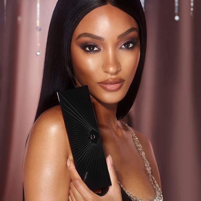 Mesmerising Holiday Look on deep-tone model Deep-tone brunette model with brown eyes wearing smokey dark green eye makeup with glowy face base and nude pink, glossy lipstick.