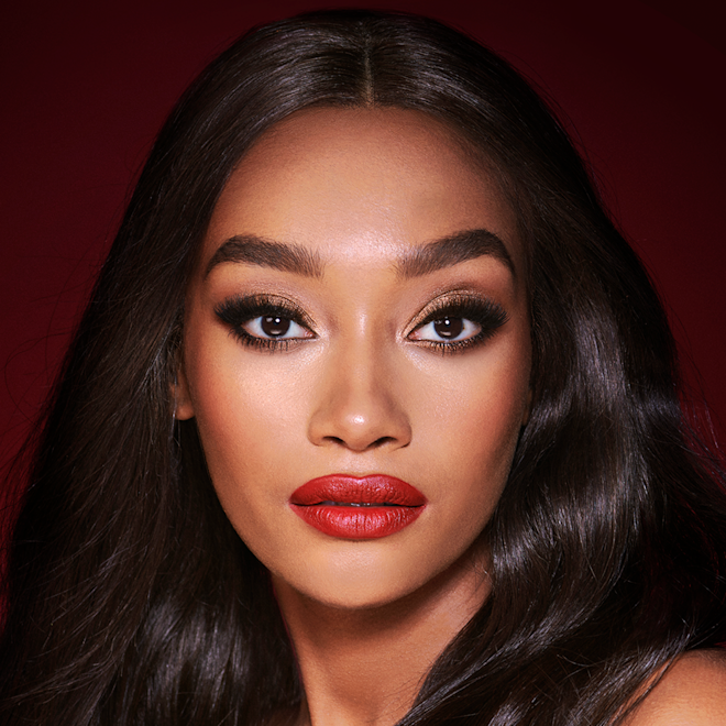 The Bombshell look on deep tone model with brown eyes A deep-tone model with brown eyes wearing shimmery bronze eye makeup with muted pink blush and glossy scarlet-red lips