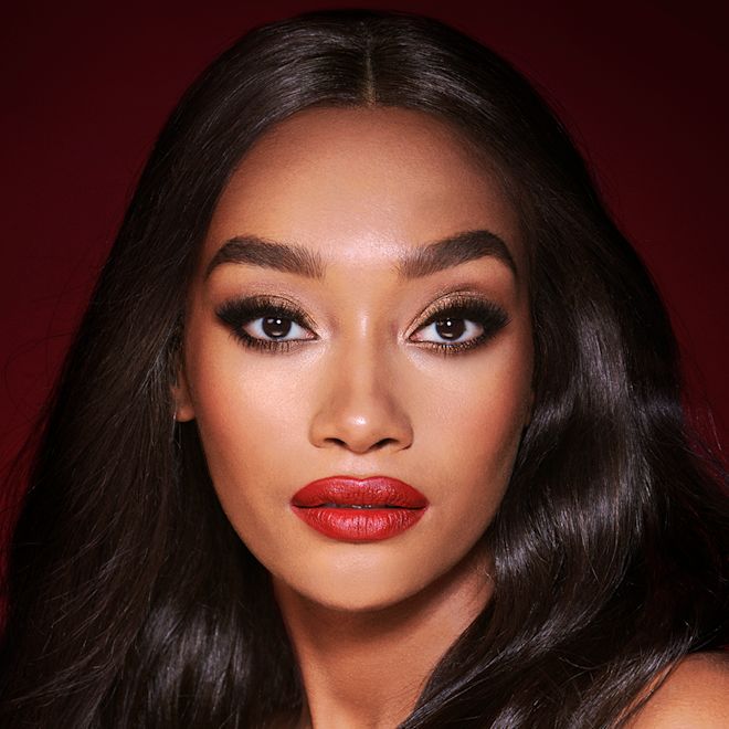 The Bombshell look on deep tone model with brown eyes A deep-tone model with brown eyes wearing shimmery bronze eye makeup with muted pink blush and glossy scarlet-red lips