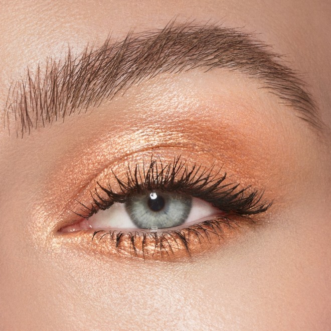 Single-eye close-up of a fair-tone model with blue eyes wearing warm sunset gold cream eyeshadow.