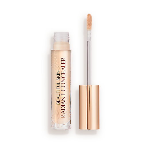 Beautiful Skin Radiant in Concealer in 2 lid removed Radiant concealer in a glass tube with its doe-foot applicator next to it with a gold-coloured handle.