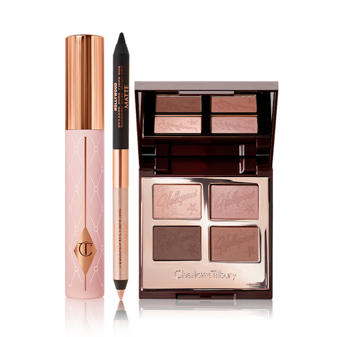 Charlotte's Hollywood Eye Filters kit displayed Mascara in a nude pink tube with a gold-coloured lid, an open, double-sided eyeliner pen in black and soft champagne-beige, and an open, mirrored-lid quad eyeshadow palette with matte and shimmery shades in gold and brown.