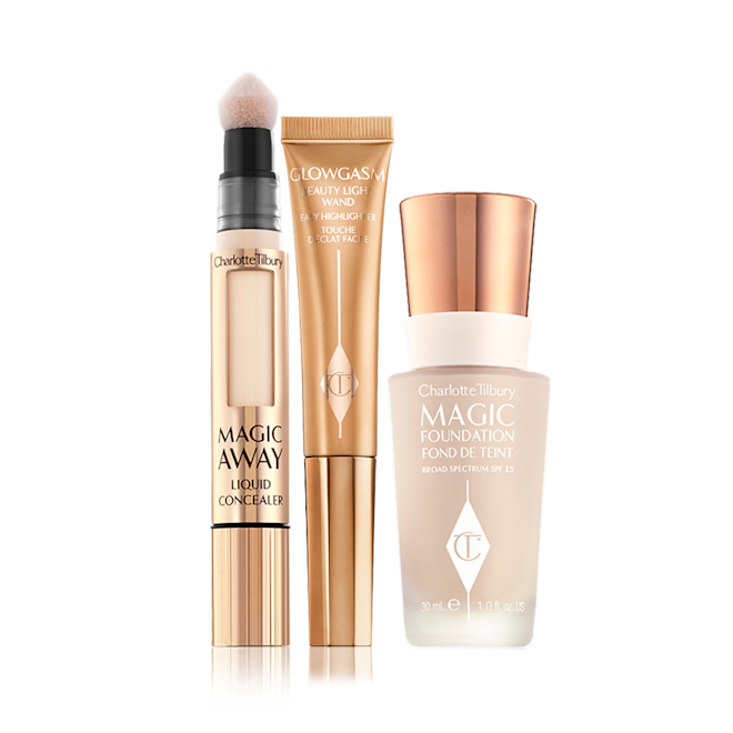 Charlotte's Magic Conceal, Retouch and Glow Kit displayed Concealer in sleek, gold-coloured tube with a soft, sponge applicator end, highlighter wand in a honey-gold-coloured tube, and foundation in a frosted glass bottle with a gold-coloured lid.