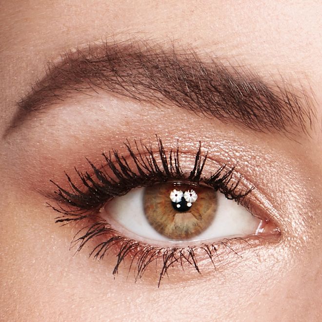 Bigger Brighter Eyes Tricks on hazel eye close-up Single-eye close-up of a fair-tone model with hazel eyes wearing shimmery champagne, light brown, and rose gold eye makeup with jet-black lengthening mascara.