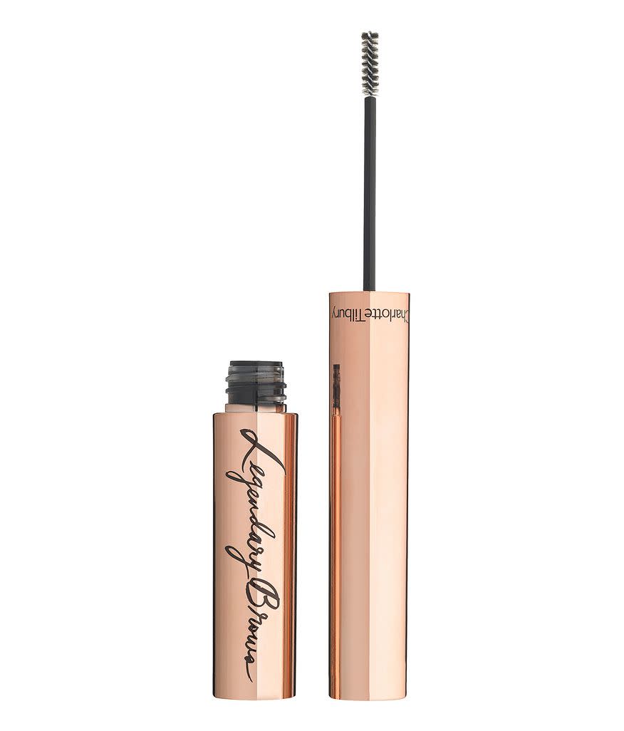 An open, brow gel in a golden-coloured tube with its thin, spoolie applicator next to it. 