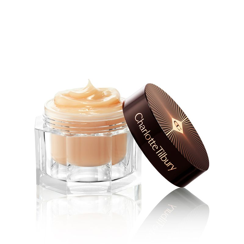 A thick, dark champagne-coloured face cream in a glass jar with its lid next to it.
