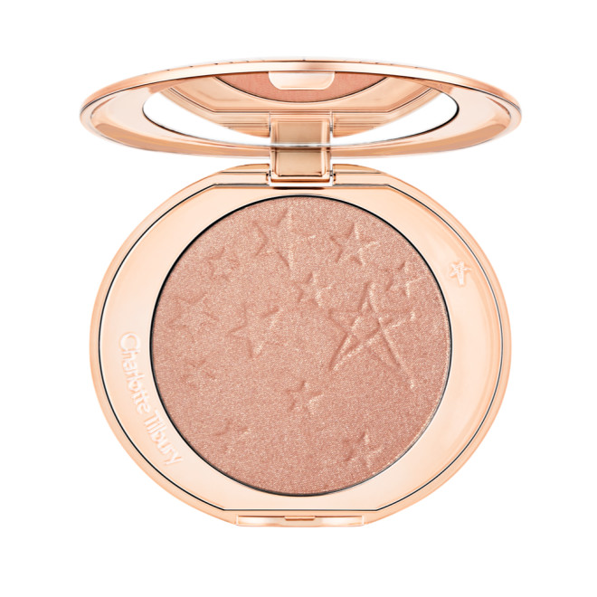 An open highlighter powder compact with a mirrored lid, in a shimmery rose gold shade. 