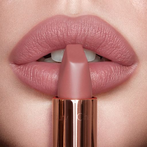 Pillow Talk Luscious Lip Slick Cat Box US Lips close-up of a model wearing a matte, nude pink lipstick while holding the lipstick in front of her lips.