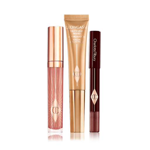 Glowing Eye, Lip and Cheek Kit closed Nude pink lip gloss in a glass tube with gold-coloured lid, a highlighter wand in a gold-colour, and a chubby eyeshadow stick in an amber-brown shade.