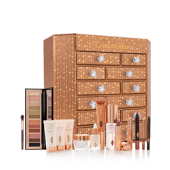 Charlotte's Instant Eye Palette Advent Calendar with products displayed A dresser with twelve different products displayed, such as luminous serum, blush highlighter wands, mascaras, eyeliner pencils, eyeshadow sticks, eyeshadow palette, and face creams.