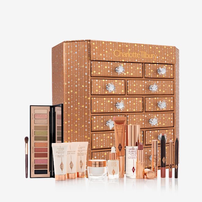 Charlotte's Instant Eye Palette Advent Calendar with products displayed A dresser with twelve different products displayed, such as luminous serum, blush highlighter wands, mascaras, eyeliner pencils, eyeshadow sticks, eyeshadow palette, and face creams.