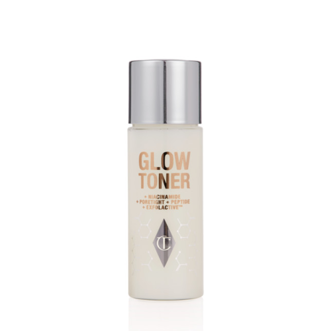 A travel-size, clear bottle filled with luminous, cream-coloured watery toner with a silver-coloured lid.