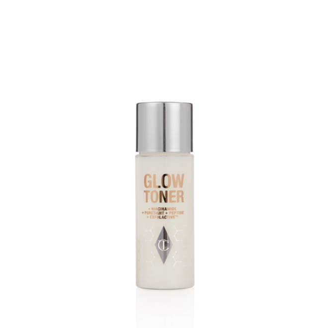 A travel-size, clear bottle filled with luminous, cream-coloured watery toner with a silver-coloured lid.