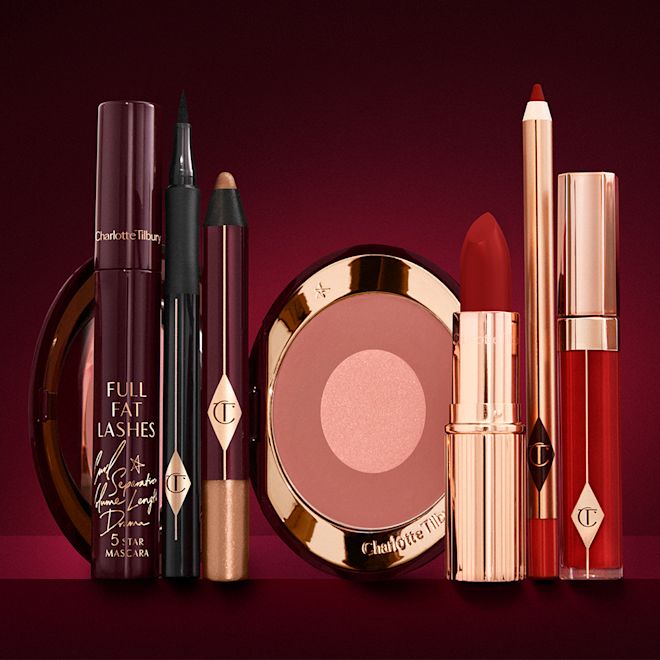 The Bombshell Deep Look kit displayed An open two-tone blush in cool-toned terracotta and warm pink with a mascara, eyeliner pen, an open lipstick in bold red, lip liner pencil in blood-red, and a lip gloss in bright red.