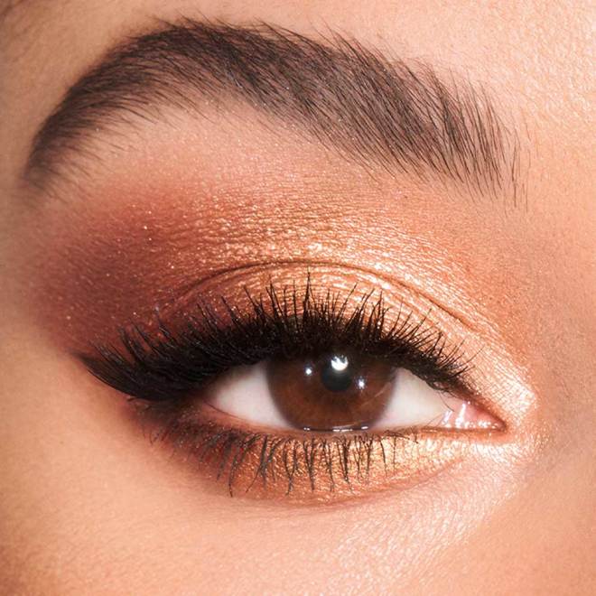Single-eye close-up of a light-tone model's brown eyes with shimmery brown, gold, and champagne eye makeup. 