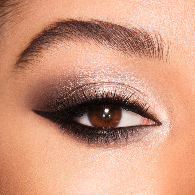 Close-up of a medium-tone model's brown eyes with smokey silver, black, and grey eye makeup. 