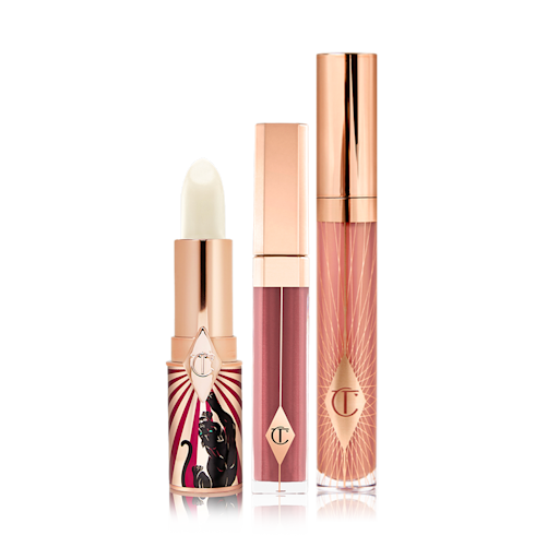 Plumper Looking Lips Kit An open lip conditioner lipstick in a white colour with two lip glosses, one a sheer berry colour and the other a nude pink.