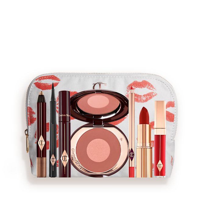 The Bombshell Deep kit with makeup bag displayed A white-coloured makeup pouch with an open two-tone blush in cool-toned terracotta and warm pink with a mascara, eyeliner pen, an open lipstick in bold red, lip liner pencil in blood-red, and a lip gloss in bright red.