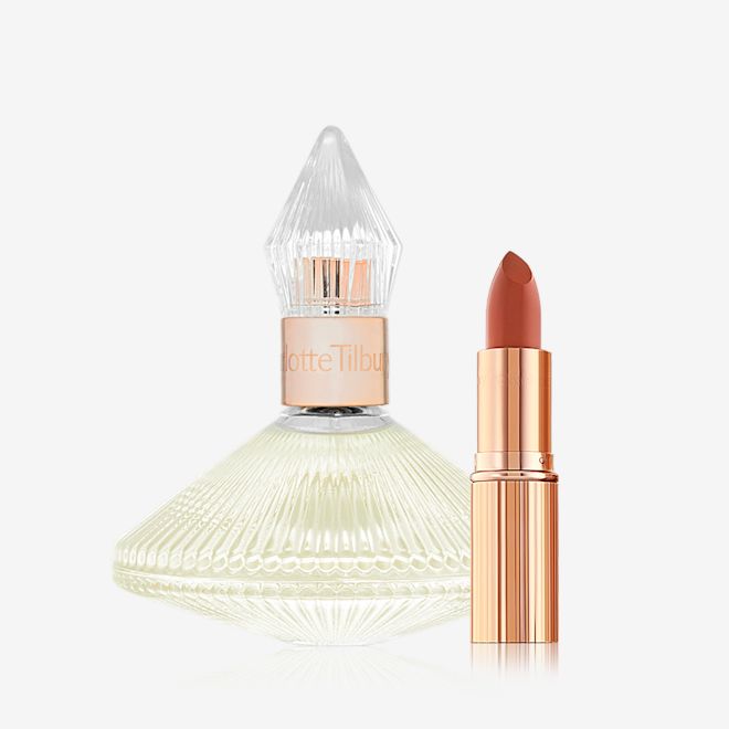 Scent of A Pillow Talk Dream Kit A 100 ml perfume in a glass bottle with a glass lid with an open lipstick in a peachy-red shade in a golden-coloured tube.