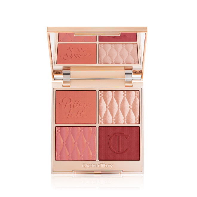 An open, face palette with matte and shimmery eyeshadows, blushes and highlighters in shades of pink, red. and gold with a mirrored lid.