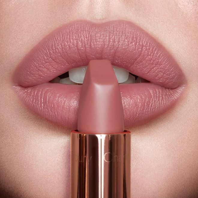Matte Revolution Pillow Talk Original on fair tone model's lips close up Lips close-up of a fair-tone model wearing a nude-pink matte lipstick while holding the lipstick in front of her lips.