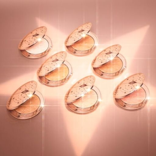 Hollywood Glow Glide Face Architect Highlighter collection open Collection of open, powder highlighter compacts in shades of gold, brown, pink, and silver in sleek, golden-coloured lids.