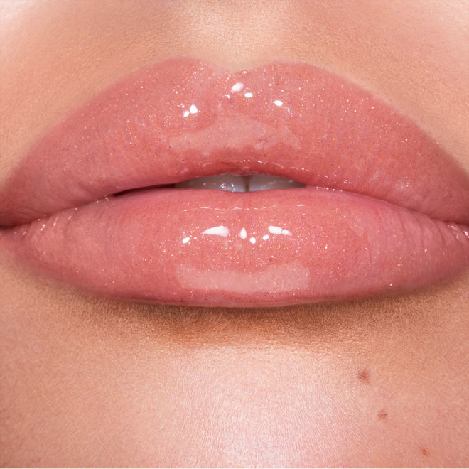 Lips close-up of a fair-tone model wearing a shimmery, gold-coloured lip gloss with rose gold sparkles.