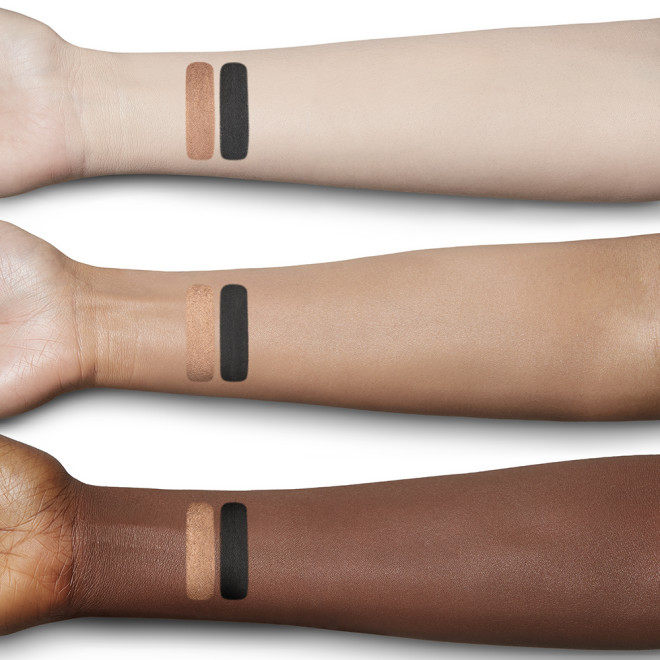 Fair, tan, and deep-tone arms with swatches of two chubby eyeshadow sticks in coppery-brown and black colours.