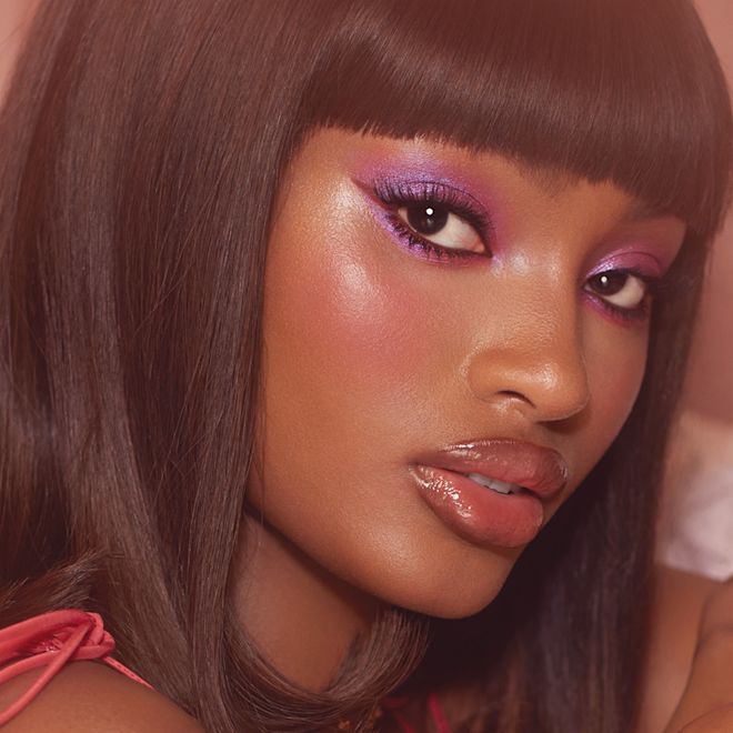 Blessing wearing Beauty Blush Wands and Beauty Light Wands A deep skin model wearing a liquid blush and liquid highlighter