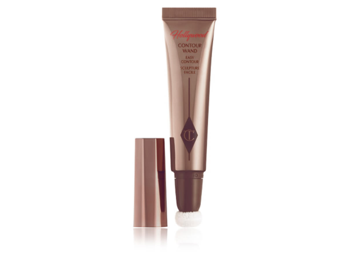 Hollywood Contour Wand open An open, liquid contour wand in a deep bronze-coloured, reflective packaging with a soft, sponge-tip applicator at the end and its lid next to it.