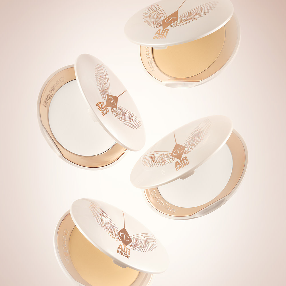 A collection of open, setting powder compacts in two shades, fair to light and medium to deep, in white and gold-coloured packaging. 