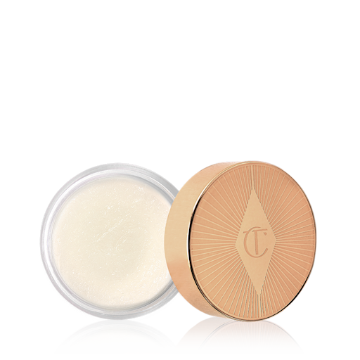 Charlotte's Magic Lip Scrub open An open pot filled with a thick, white-coloured lip scrub with its gold-coloured lid next to it.