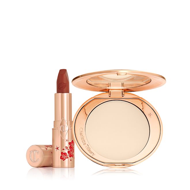 Airbrush Skin Lucky Lip Kit open A matte burnt-orange red lipstick in gold-coloured packaging with cherry blossoms illustrated on the tube for the Lunar New Year, along with its lid next to it and an open, pressed powder compact for fair skin tones with a mirrored lid, in gold-coloured packaging with red-coloured cherry blossoms on the lid.