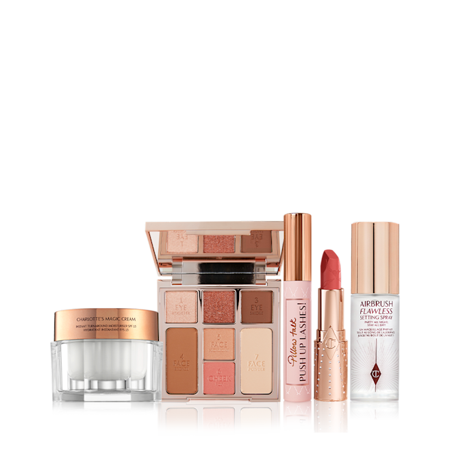 Look of Love bundle 3 displayed An open, mirrored-lid face palette with nude eyeshadows, nude pink and soft pink blushes, bronzer, and highlighter, an open lip liner pencil in nude pink shade, black mascara with nude pink tube with a gold-coloured lid, an open lipstick in a coral-pink shade in a gold-coloured tube, pearly-white cream in a glass jar with a gold-coloured lid, and setting spray with a gold-coloured lid.