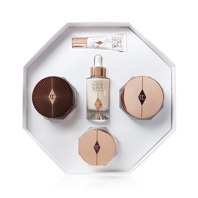 An open skincare kit with two face creams, eye cream, luminous face serum, and eye serum, in a hexagon-shaped gift box. 