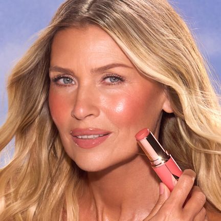 Unreal Blush Peachy Glow Model Medium model wearing and holding peach tone blush.