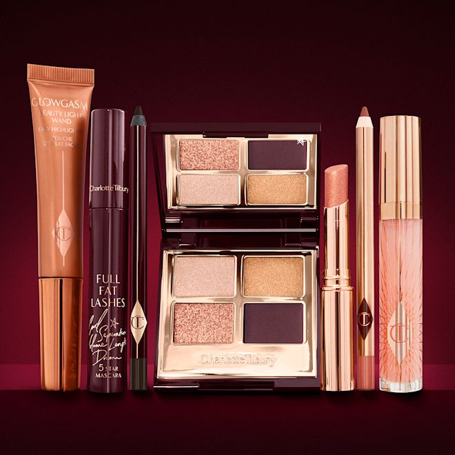 The Queen of Glow Look kit displayed A highlighter wand in a copper-gold-coloured tube with a mascara, eyeliner pencil, quad eyeshadow palette with shimmery and matte rose gold, plum, and golden shades, an open lipstick in nude coral, lip liner pencil in nude red, and a lip gloss in nude pink.