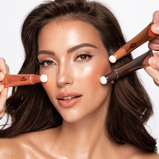 Beauty Light Wands on medium-tone brunette model Medium-tone brunette model wearing glowy, nude coral-pink soft glam makeup look while getting blush and contour applied from liquid highlighter blush wands and a liquid contour wand.