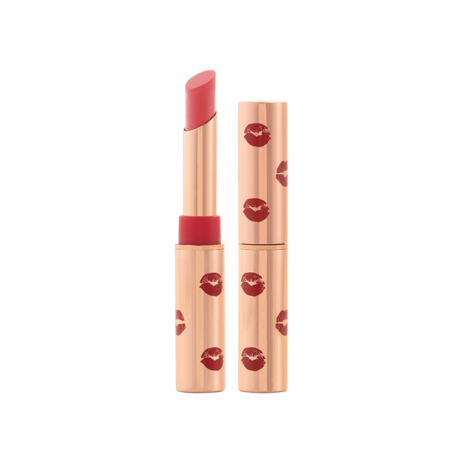 Two identical lipsticks, with and without lid, in a neutral rosy-pink colour with a matte finish, in gold-coloured tubes with red-coloured kiss print all over the tube.