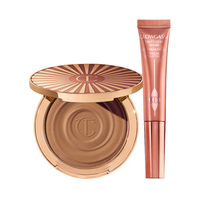 An open cream bronzer compact with gold-coloured packaging with a highlighter blush wand in a medium-pink colour in sleek, reflective, medium-pink colour packaging.