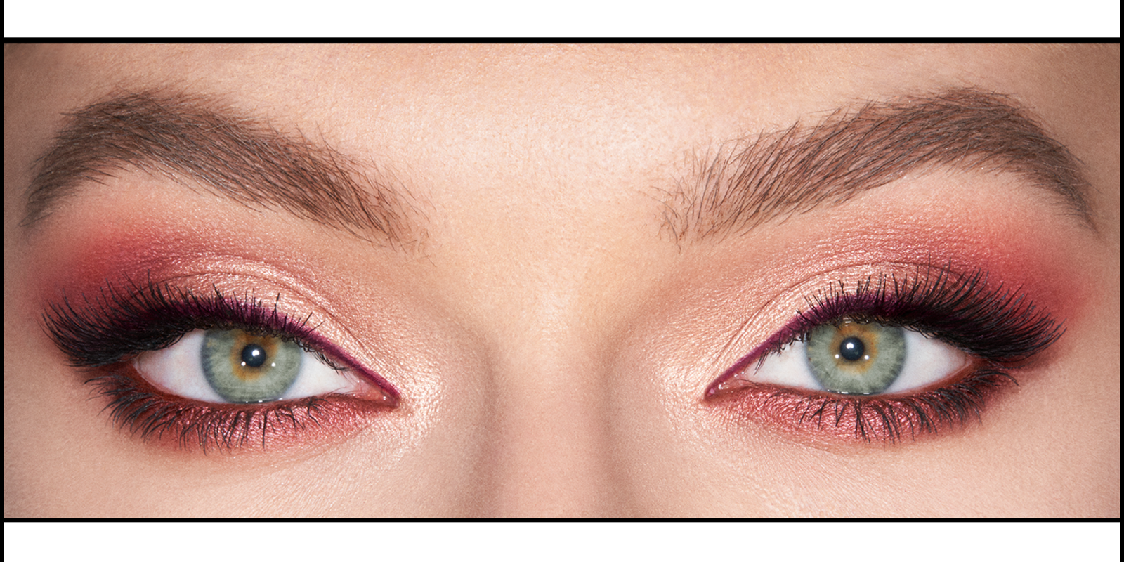 Eye close-up of a light-tone model with green eyes wearing shimmery copper and rose gold eyeshadow with maroon and rust eyeliner. 