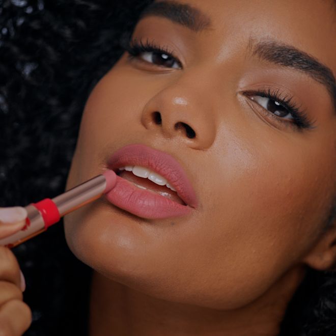 Limitless Lucky Lips in Rose Hope on deep-tone model A deep-tone brunette model wearing a neutral rosy-pink lipstick with a matte finish.