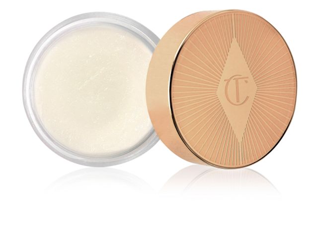 Charlotte's Magic Lip Scrub open An open pot filled with a thick, white-coloured lip scrub with its gold-coloured lid next to it.