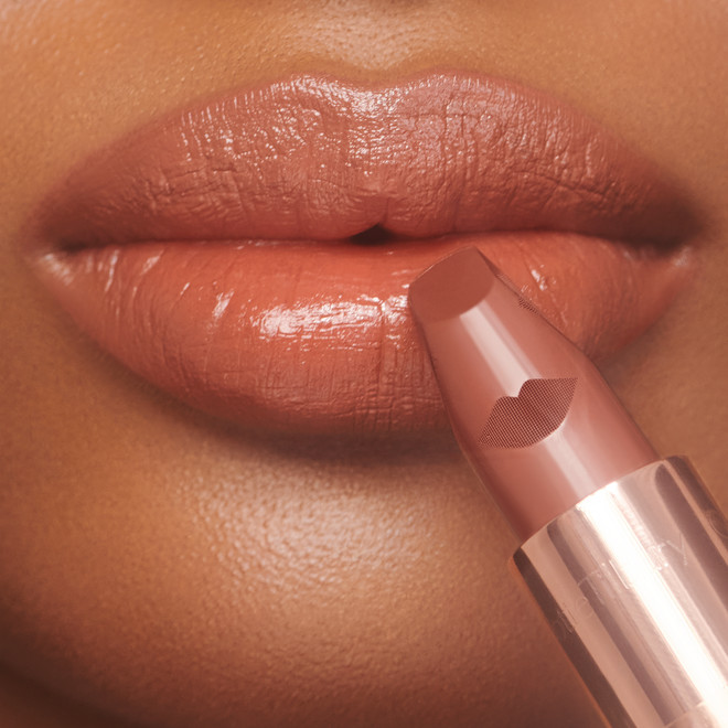 Lips close-up of a deep-tone model wearing a rosy terracotta coral lipstick with a satin-finish.