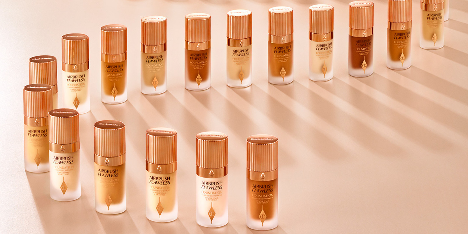 Banner with a collection of full coverage foundation in frosted glass bottles with rose-gold-coloured lids for all skin tones. 